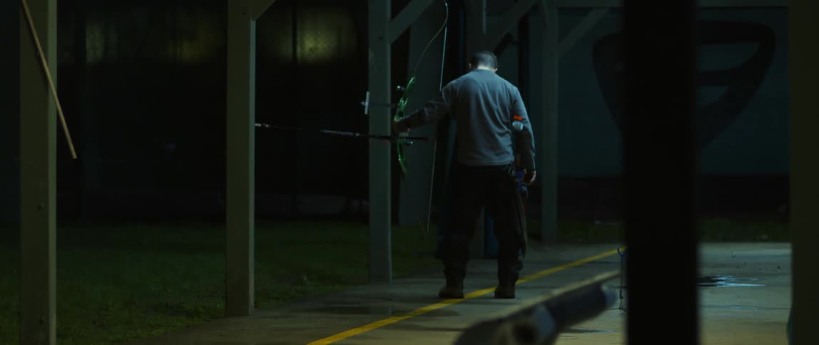 A man hold a bow and arrow at night