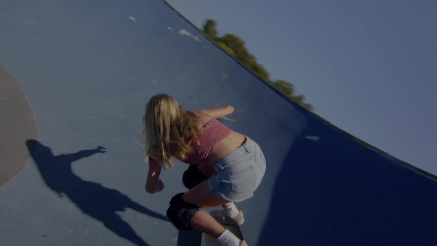 A blonde woman skateboarding on a rink