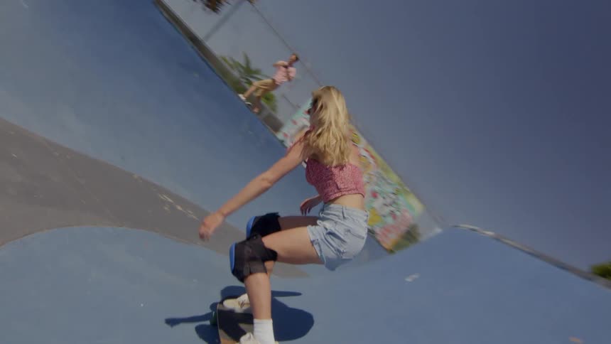A blonde young woman skateboarding on a grey rink