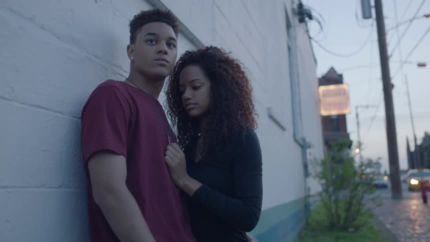 A woman is leaning against a man who is by a building