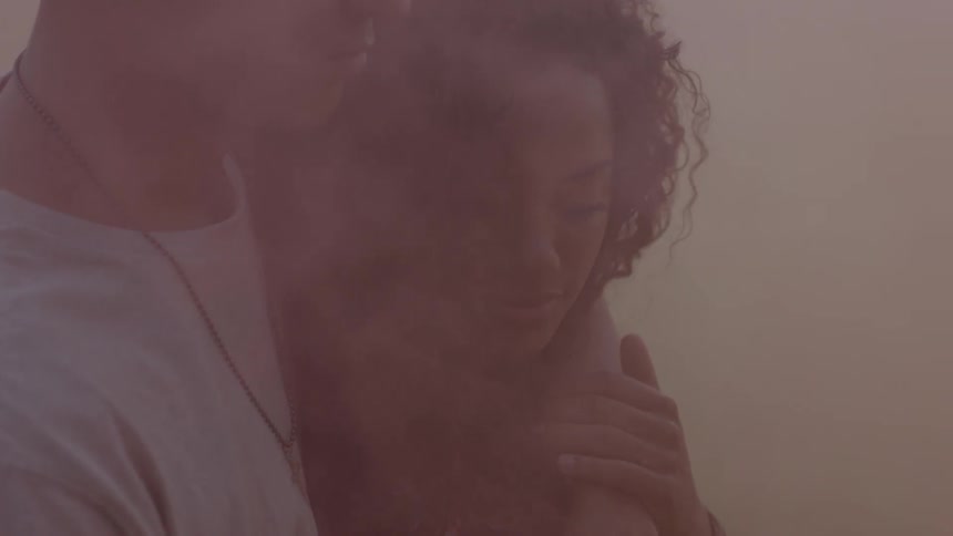 A man holds a woman with smoke all around