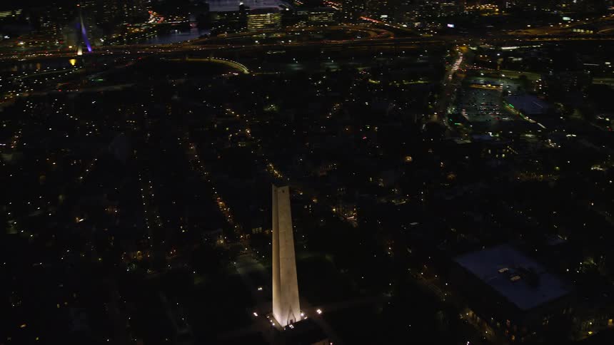 Aerial of buildings and a tall monument in a metropolitan area at night