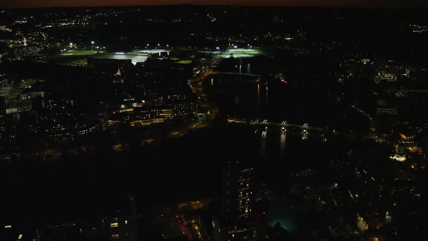 A city at night with lights on and a river running through the middle with bridges