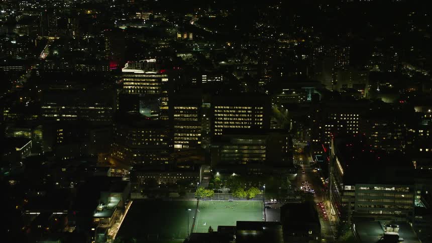 Highrise buildings and a sports field in a city at night