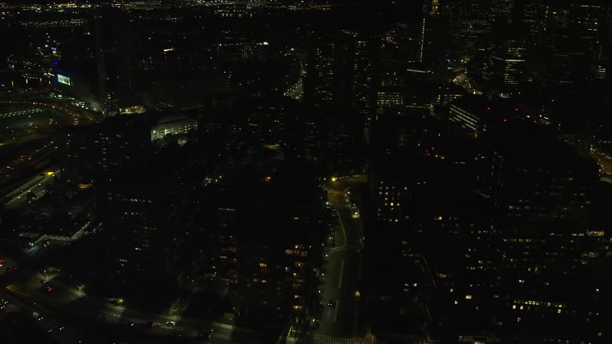 A night city with residential lights on and cars passing on the streets