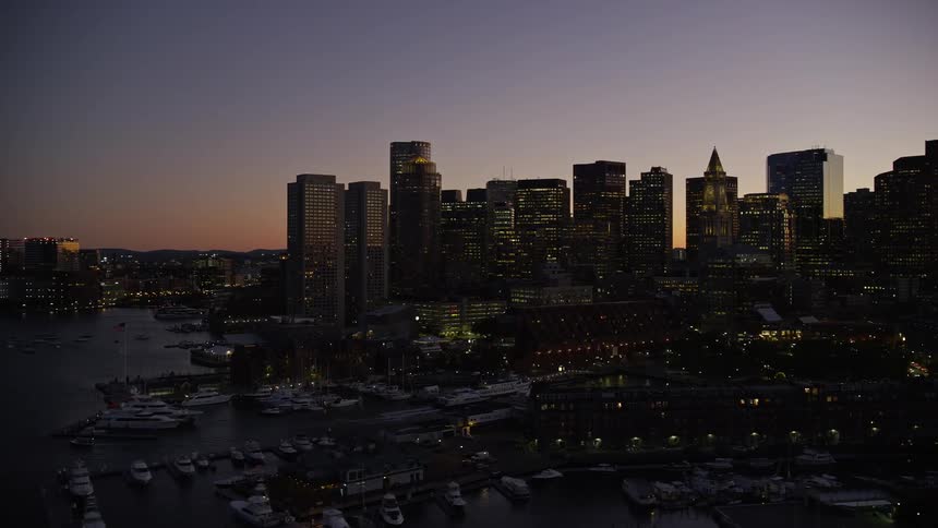 Many tall buildings in a metropolitan city near the coast with marinas and boats