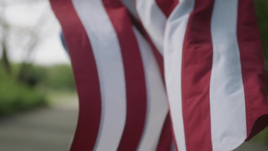 A person is running with an american flag flying behind