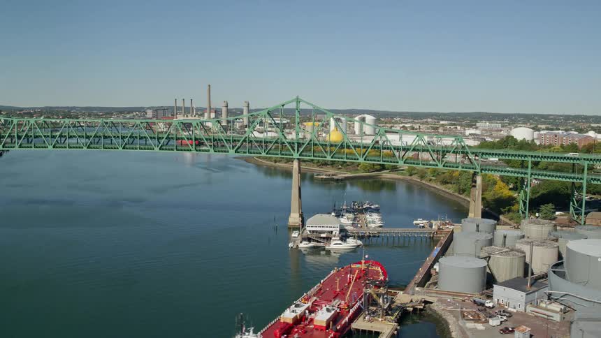 Moving cars on a metal bridge over a river at midday