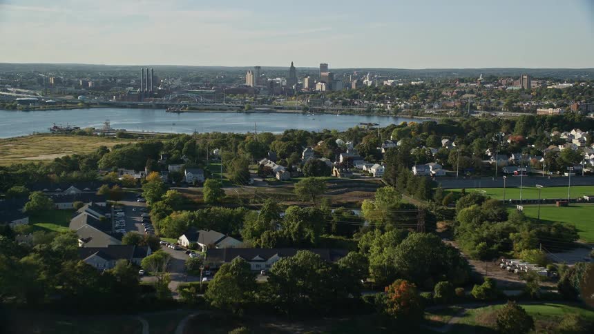 A daytime aerial view of a park and lake before a large city