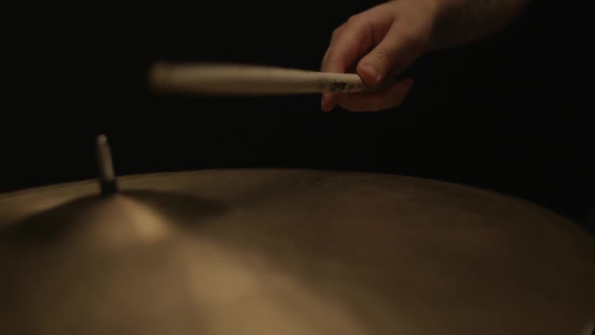 A man is playing the drums in a dark room