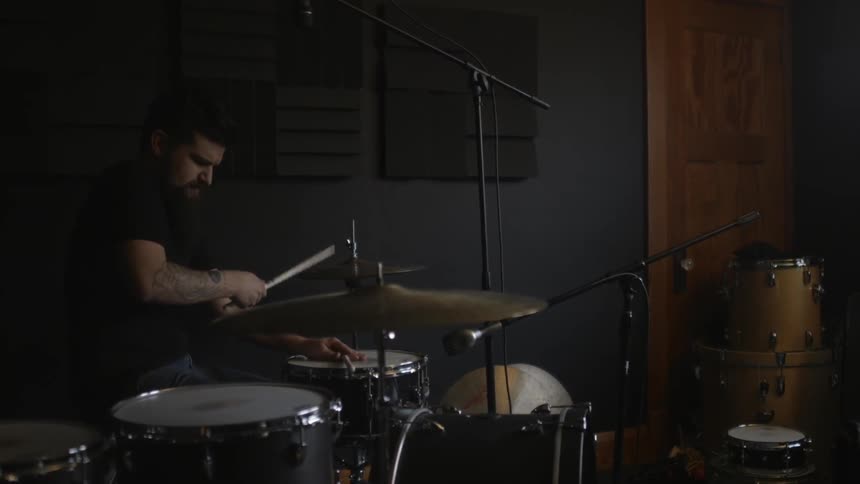 A man is playing drums with a stick and his hand