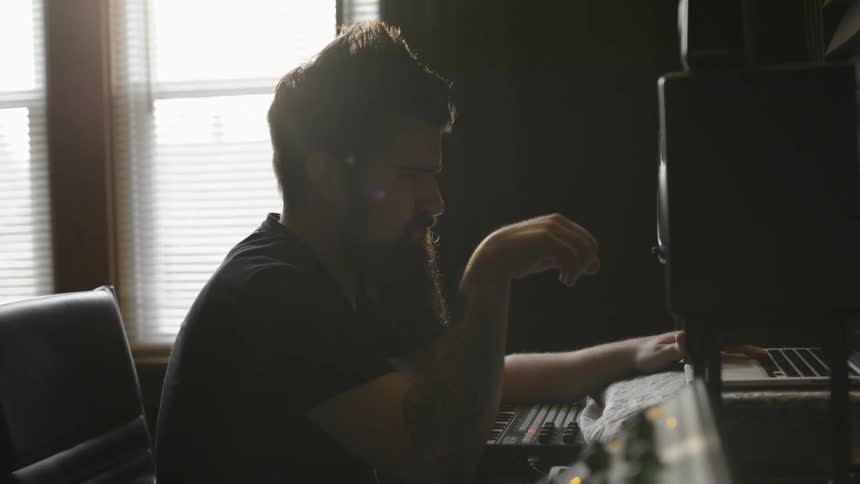 A man is using a laptop in a music studio