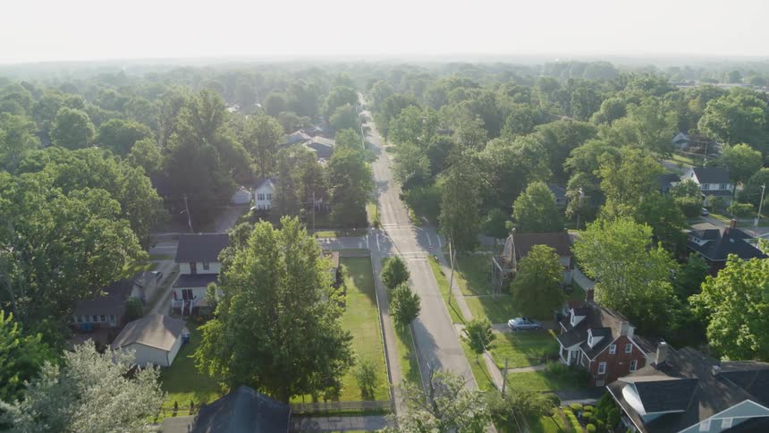 Tall trees and green lawns surround the homes of a working class residential neighborhood