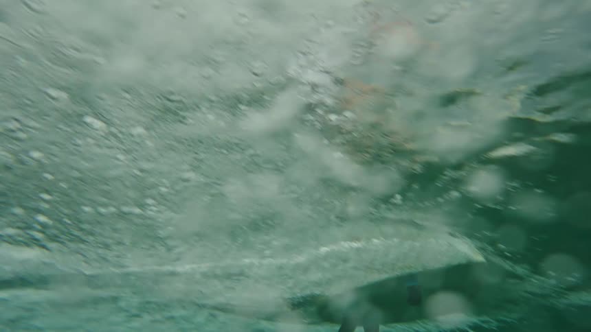 Surfer rides surfboard creating wake underneath water