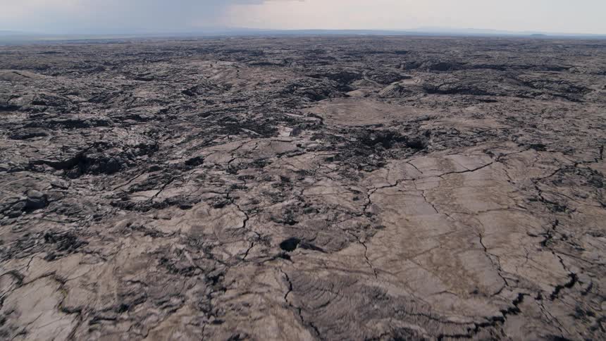 Skimming low over the otherworldly terrain of endless cracks and fissures atop a basalt lava field