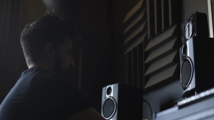 A man is bobbing his head near some speakers