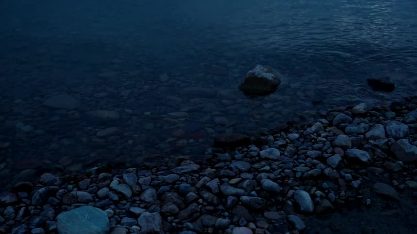 Small waves and ripples over the pebbles on the shoreline