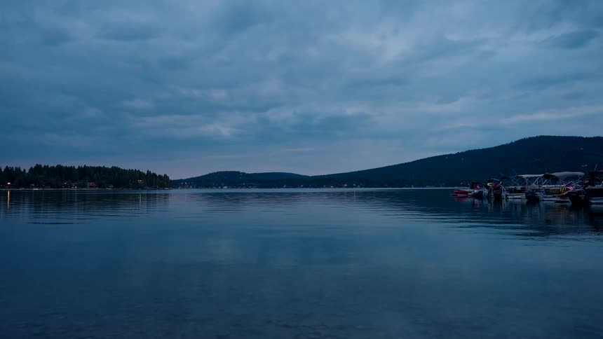 Reflective water flows from forest covered coast and pastmarina on a cloudy day