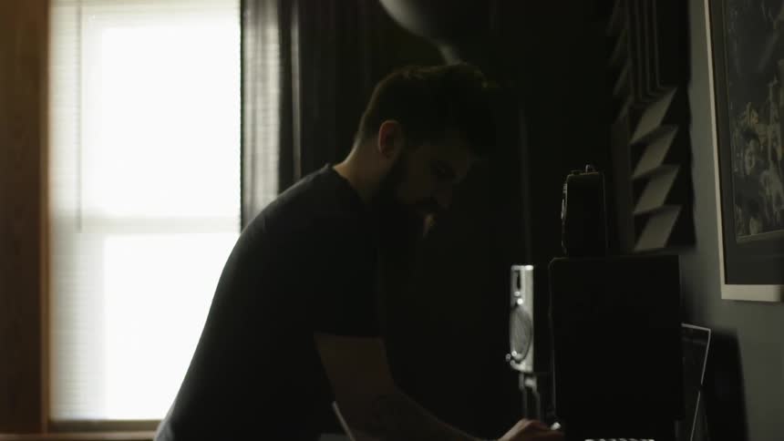 A man is standing over a computer in a dark room