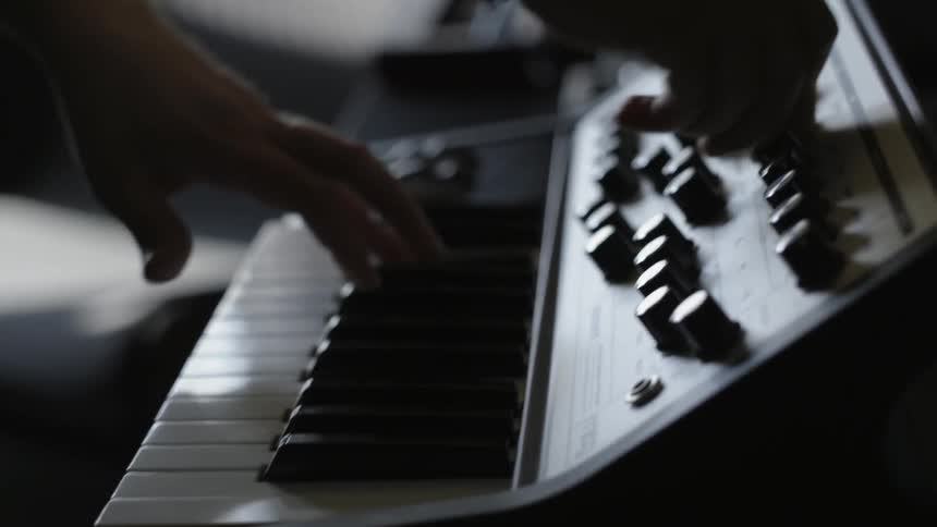 A man is adjusting knobs and using a keyboard