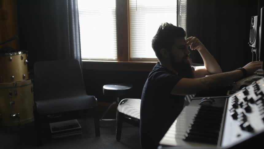 A man is touching his head as he types on a computer