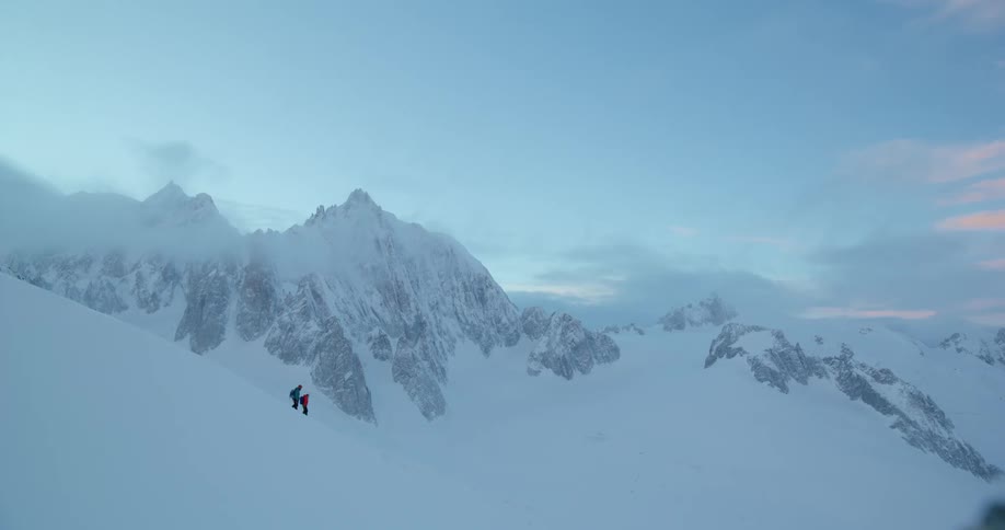 Two people descending a snowcovered mountain peak
