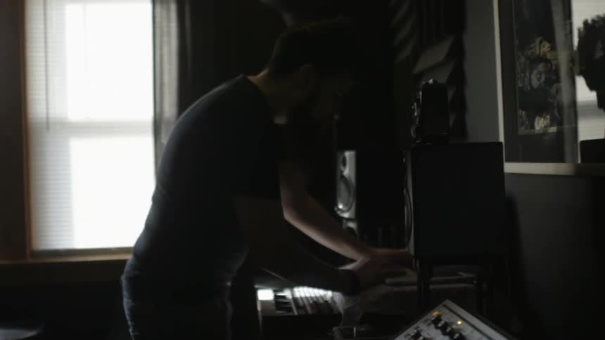 A man is standing in a room playing a keyboard
