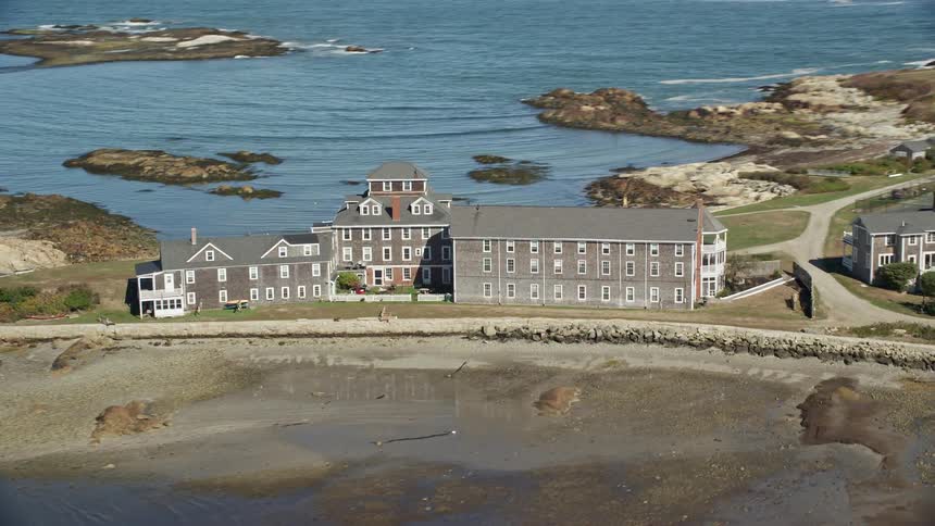 Aerial view of a waterfront mansion and adjacent property on a promontory by the ocean