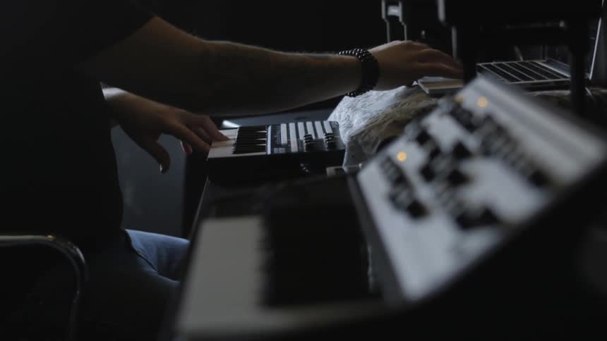 A man is playing the keyboard and using a laptop
