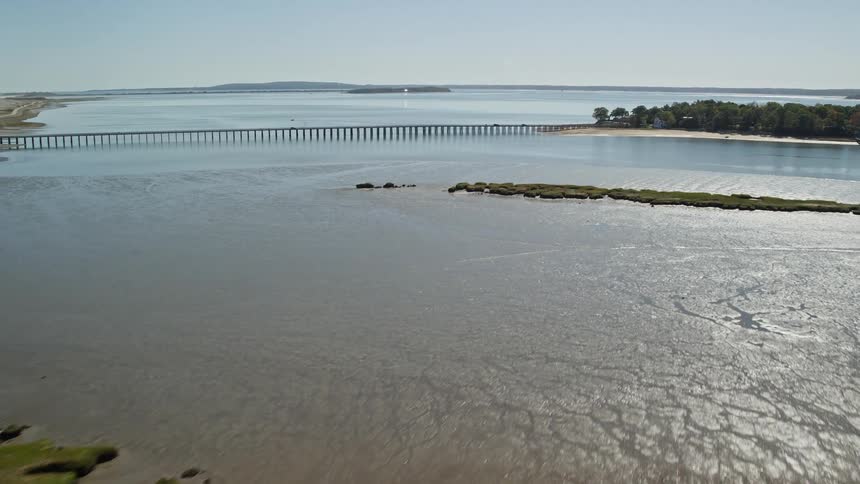 Drone flight over a marsh area and near a bridge in a coastal area by the ocean