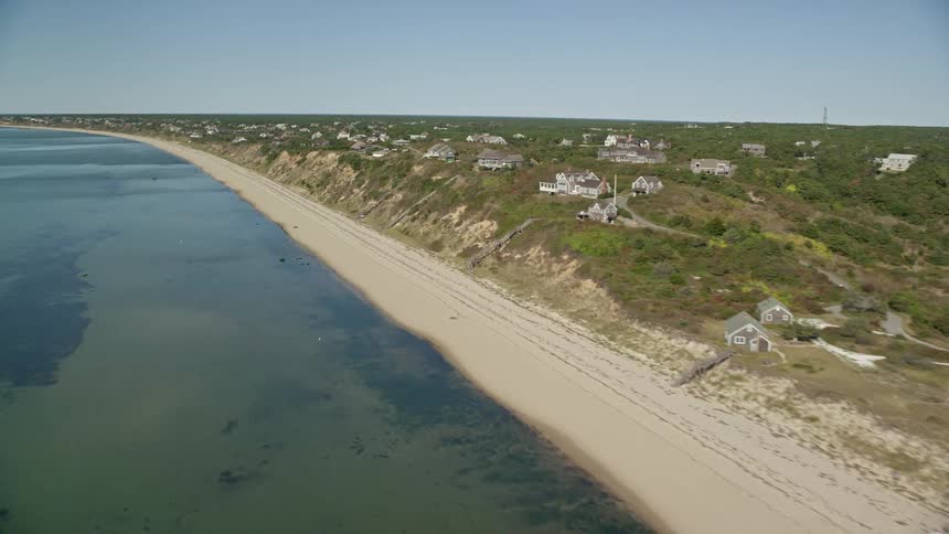 A large beachfront with several houses on top of the nearby hills