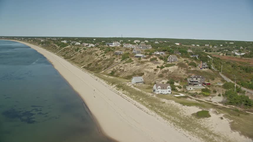Drone flight over a beach and the waterfront hills of a coastal town