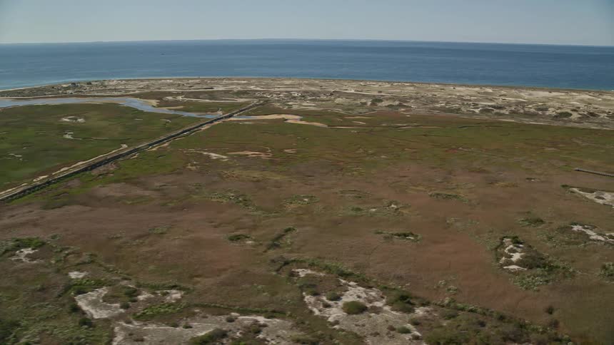 Aerial view of a road and an airfield on a coastal grassland near the ocean