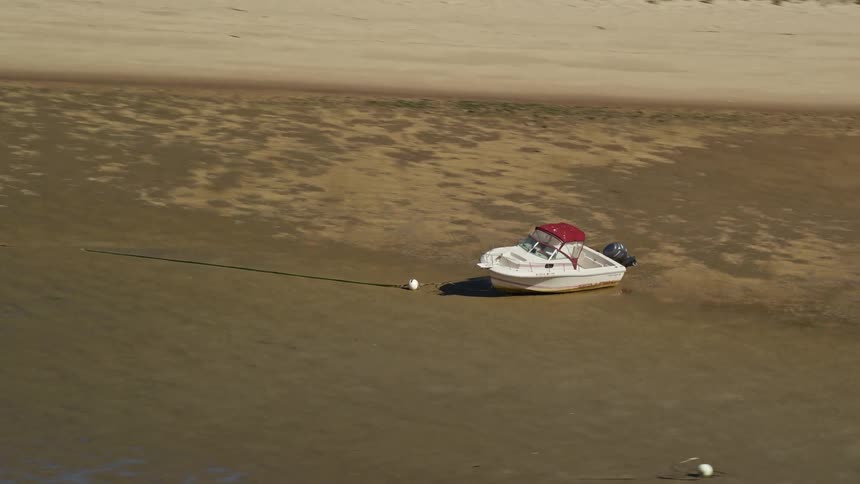 A small white boat stranded on a beach without water