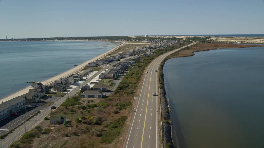 Traffic moves along roads past housing on narrow strip of land bordered by water on both sides