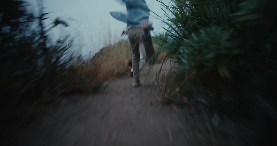 Two children are running up a hill on a trail into the woods