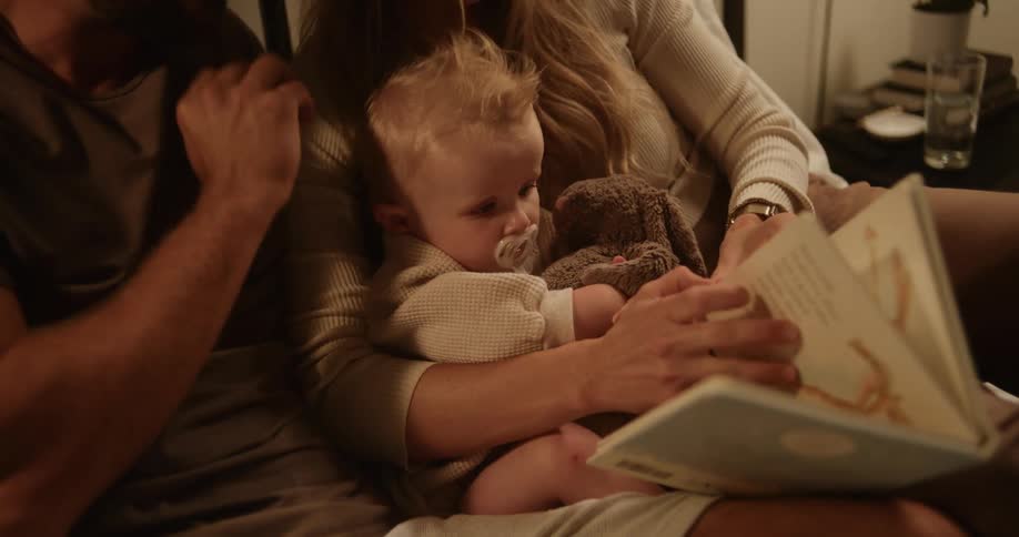 Parents reading a story book with their baby