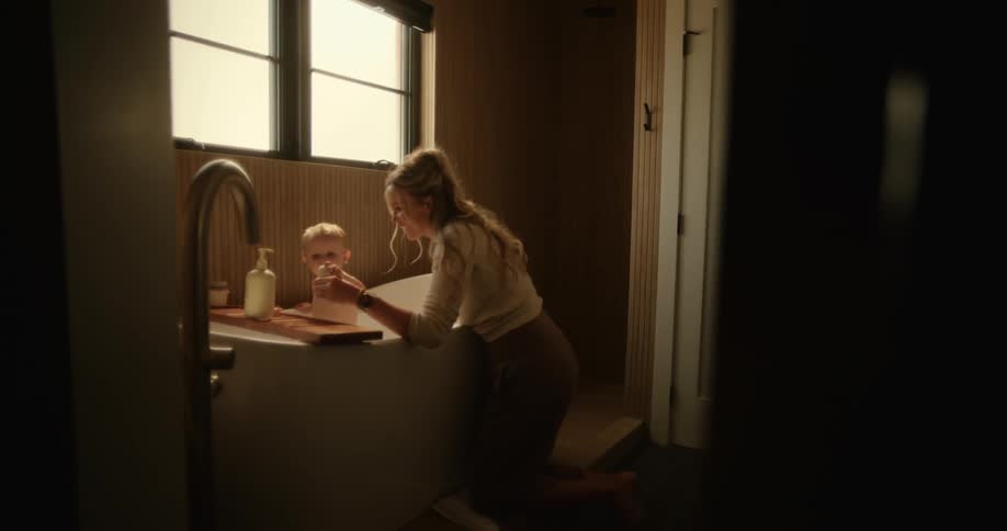 A young mother bathing her son in the bathtub