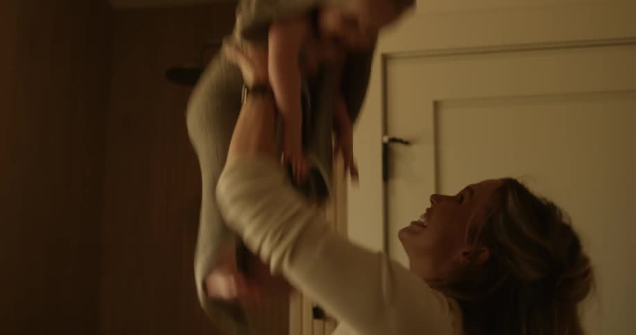 A man and a woman playing with a baby and the woman throws it up and gives it toys