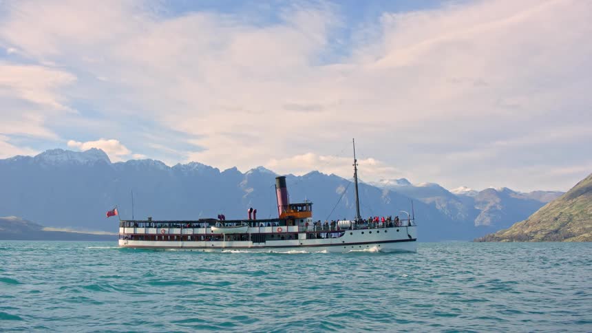 Tourist boat moving on the lake with mountain range in the horizon