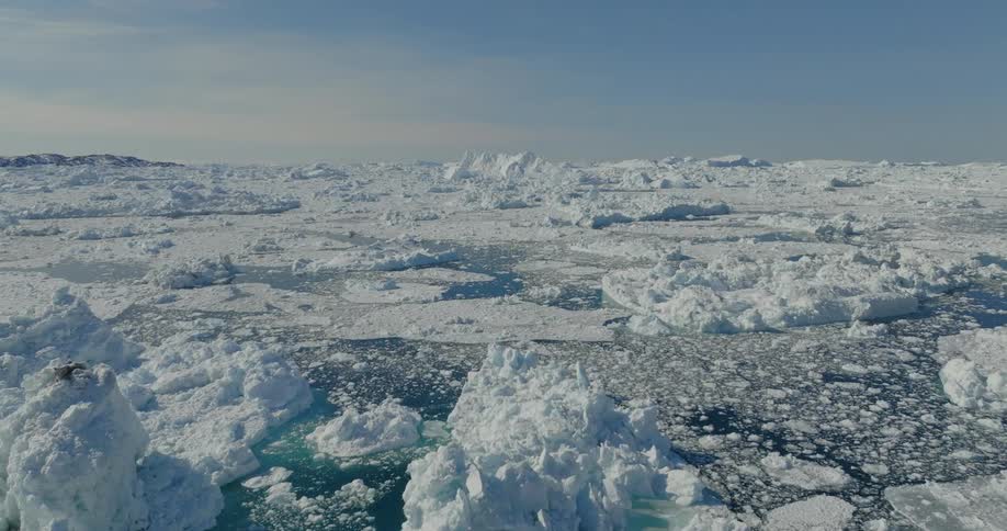 An aerial view of ice and icebergs floating in a deep blue sea