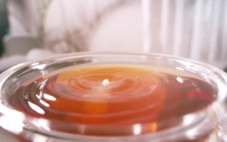 Water drops into a cup of tea as it forms into a bubble