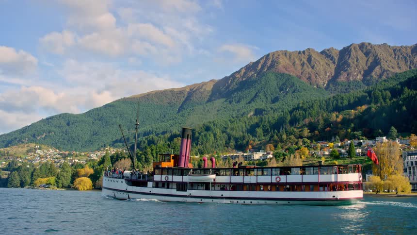 A vessel sailing on a lake and behind a mountain town