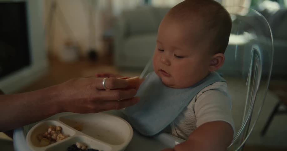 A baby sitting in a highchair eating an apple