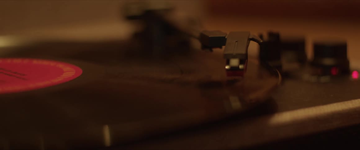 A human hand working on a vinyl record player