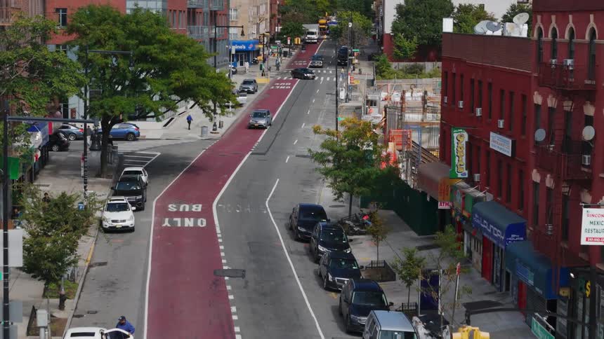 Pedestrians and cars move along city street passing by construction site