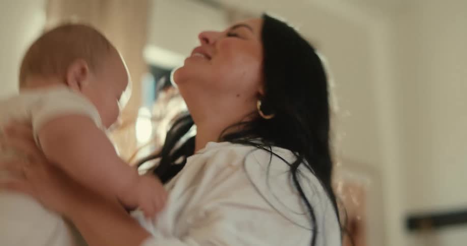 A mother playing with a baby throwing him up and hugging him