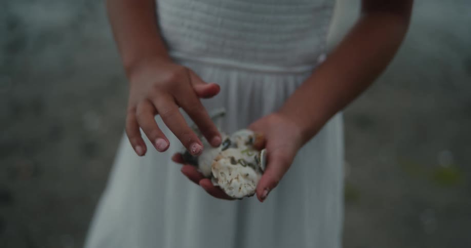 A child holding rocks and picking some off from her hands
