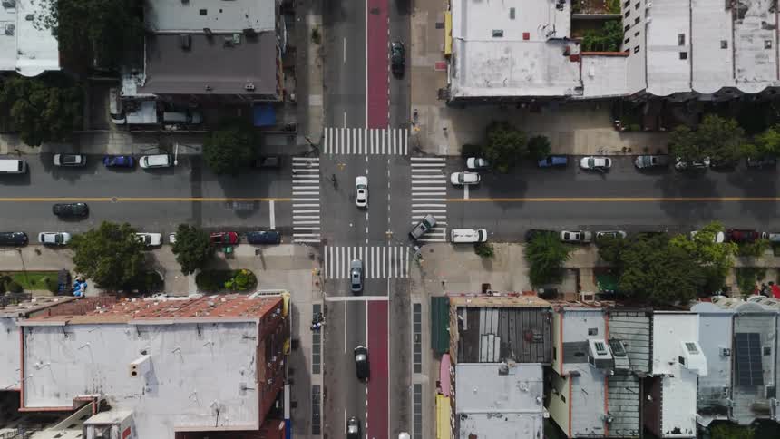 Top down aerial view of cars crossing an intersection in the city