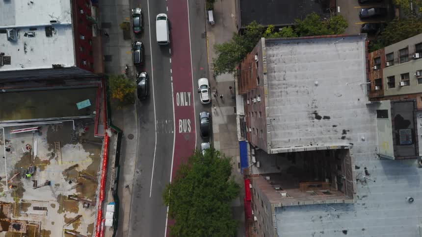 Traffic moves slowly on city streets as people walk on the sidewalk near buildings